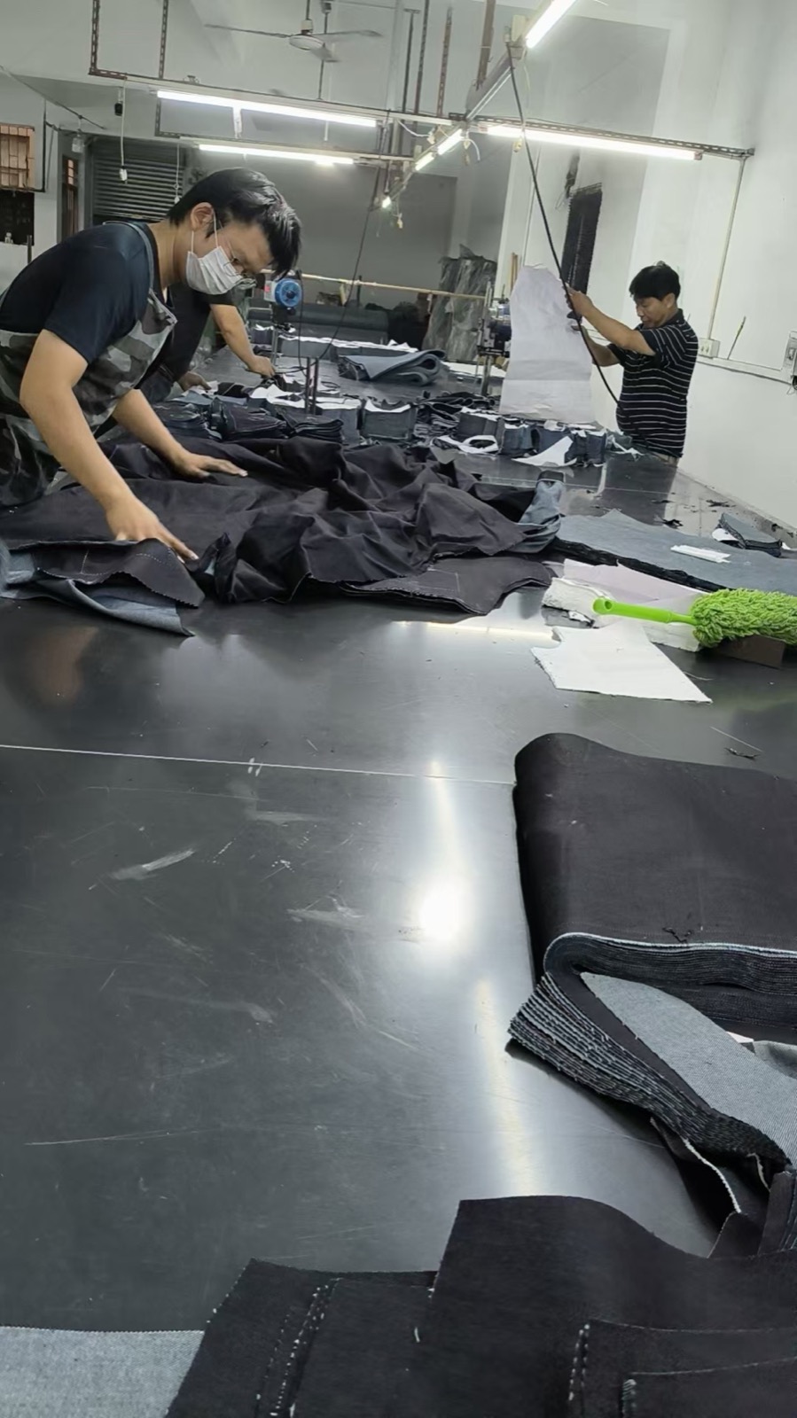 Workers preparing cut denim components on a production table