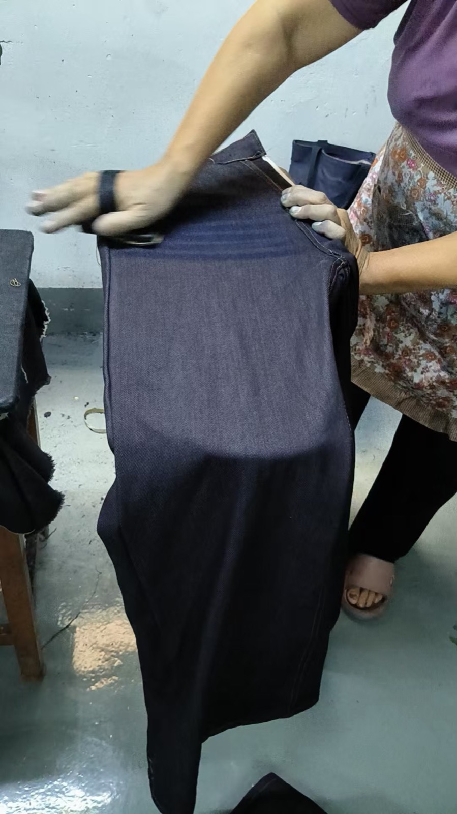 Worker pressing a denim garment during finishing
